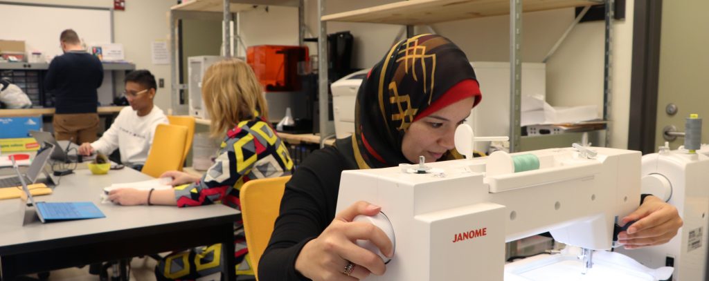 CIL students working in the lab, one is using an embroidery machine