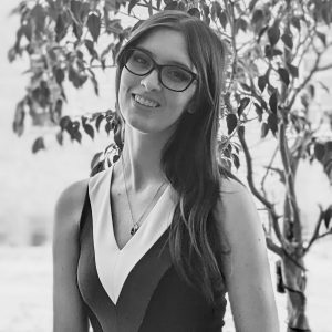 Black and white image of Georgia. She is a caucasian woman with long brown hair and black thick framed glasses.